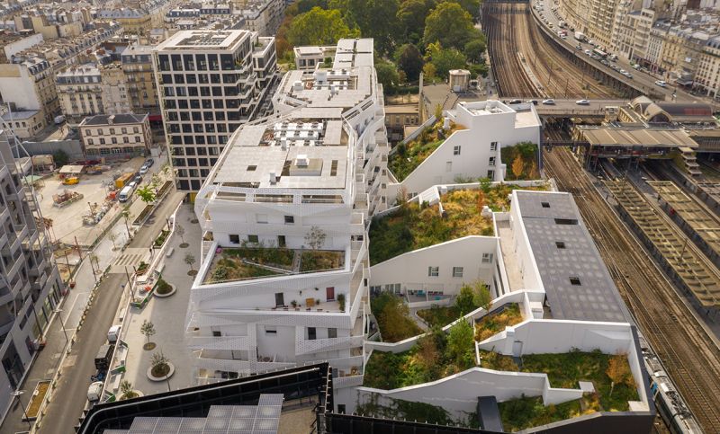 La silhouette découpée des programmes de logements permet une transition douce entre le Paris haussmannien et le nouveau quartier, la trame sobre des façades en béton blanc faisant écho à la pierre du vieux Paris.